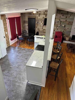 A kitchen with a granite countertop, wooden flooring, and a red curtain. - KU Lake & Golf House (Pet Friendly) (Lawrence)