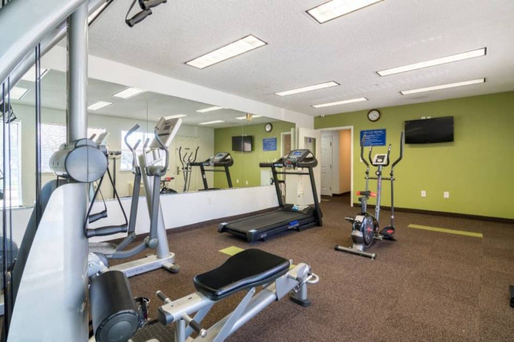 A gym with cardio machines, a treadmill, and weight equipment.