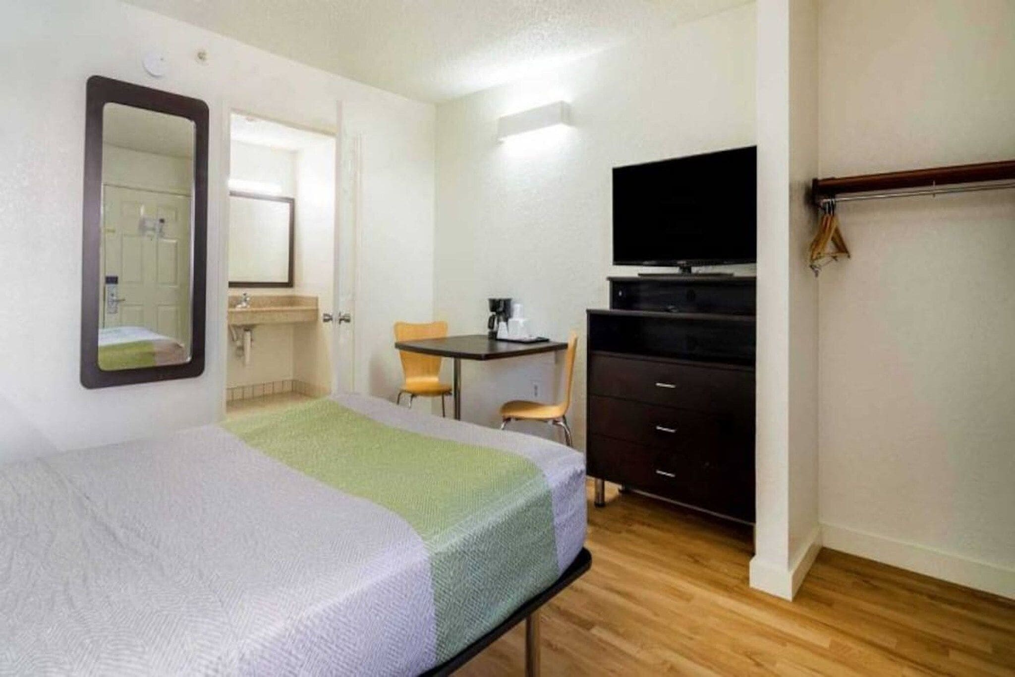A hotel room with a bed, a desk, a chair, a television, and a wardrobe.