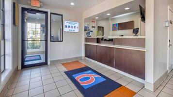 A reception area with a tiled floor, a reception desk, a digital screen, and a sign welcoming smart travelers.