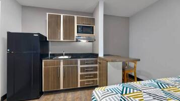 A compact kitchen with a refrigerator, microwave, sink, and wooden cabinets.