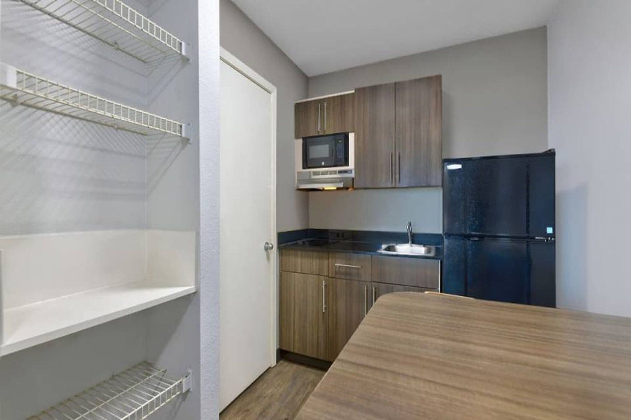 A compact kitchen with a microwave, refrigerator, and wooden cabinets.