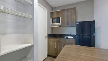 A compact kitchen with a microwave, refrigerator, and wooden cabinets.
