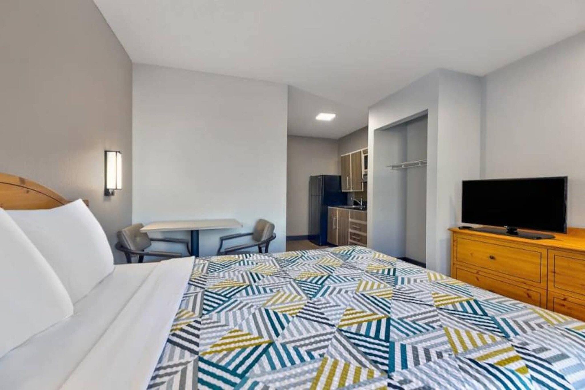 A hotel room with a bed, a desk, a television, and a wardrobe.