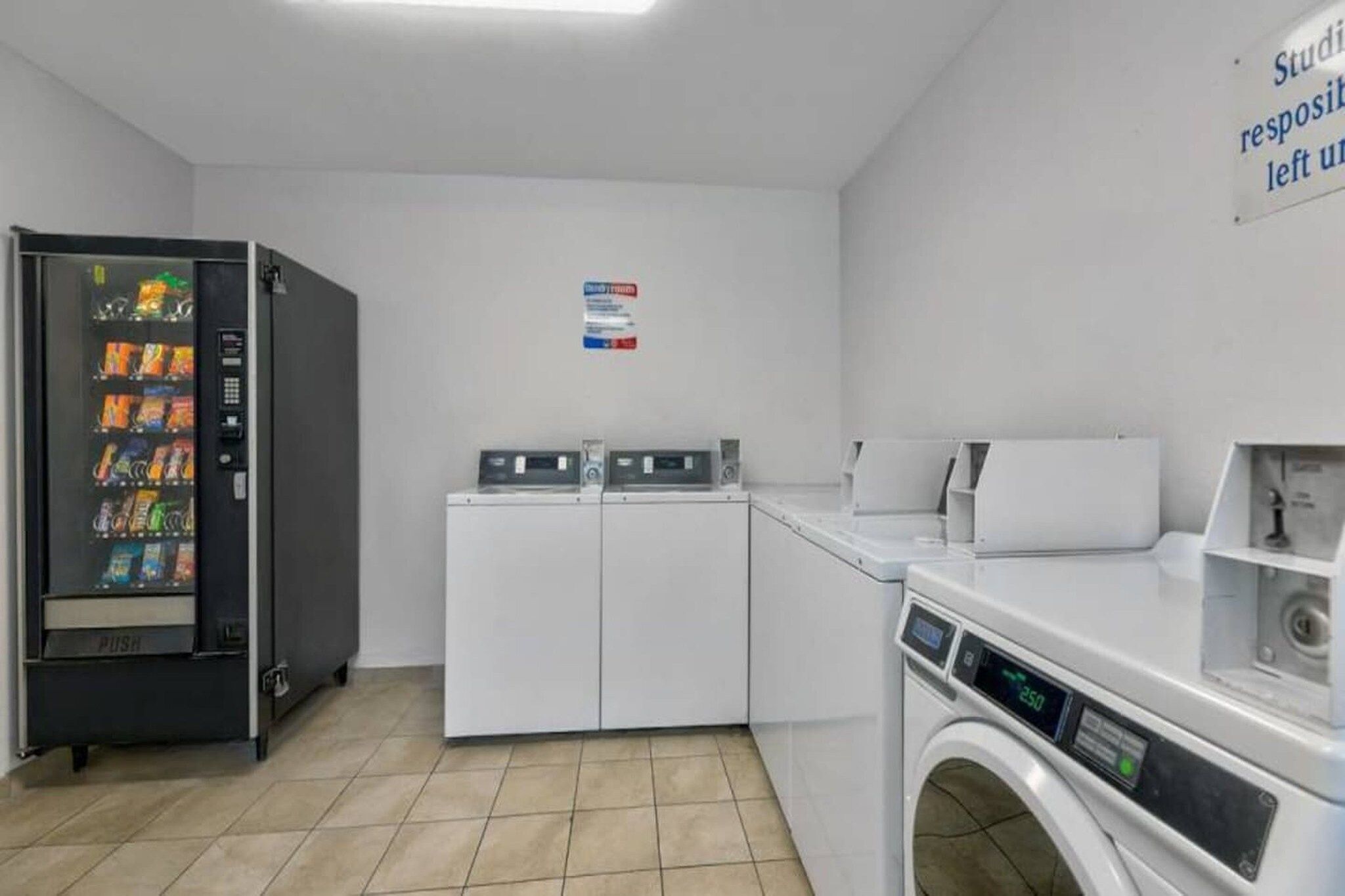 A laundry facility with a vending machine, washing machines, and dryers.