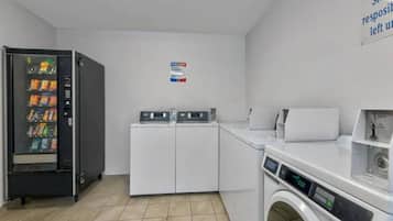 A laundry facility with a vending machine, washing machines, and dryers.