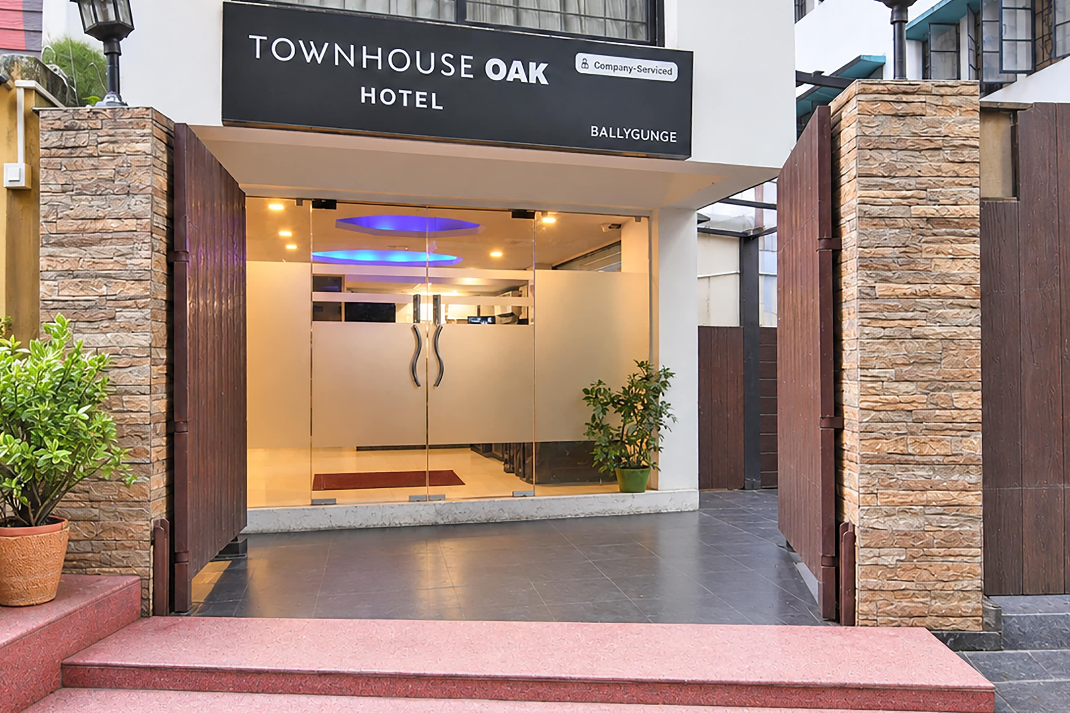 The entrance to the Townhouse Oak Hotel with a stone facade, a clear glass door, and a sign indicating it is company-serviced.