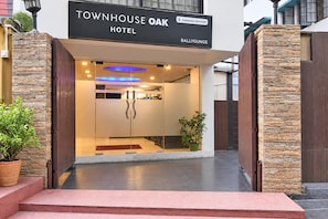 La entrada al Townhouse Oak Hotel, con fachada de piedra, puerta de cristal transparente y cartel que indica que ofrece servicios para empresas.
