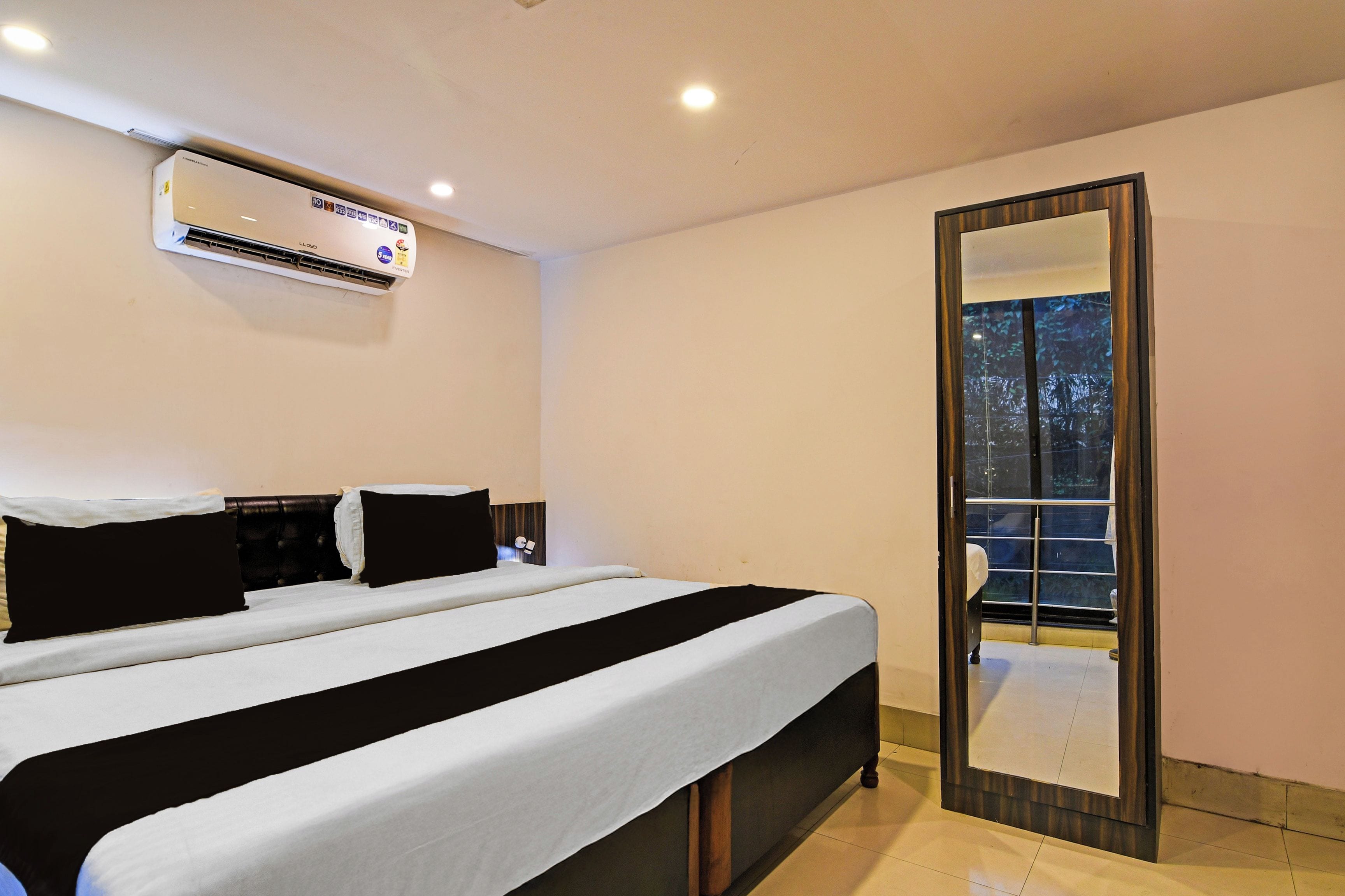 Una habitación de hotel con una cama grande, un espejo y un equipo de aire acondicionado.