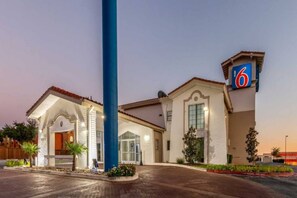A hotel with a prominent '6' sign, a covered entrance, and a well-lit facade. - Elegant 1 King Bed | Non-Smoking (EULESS)