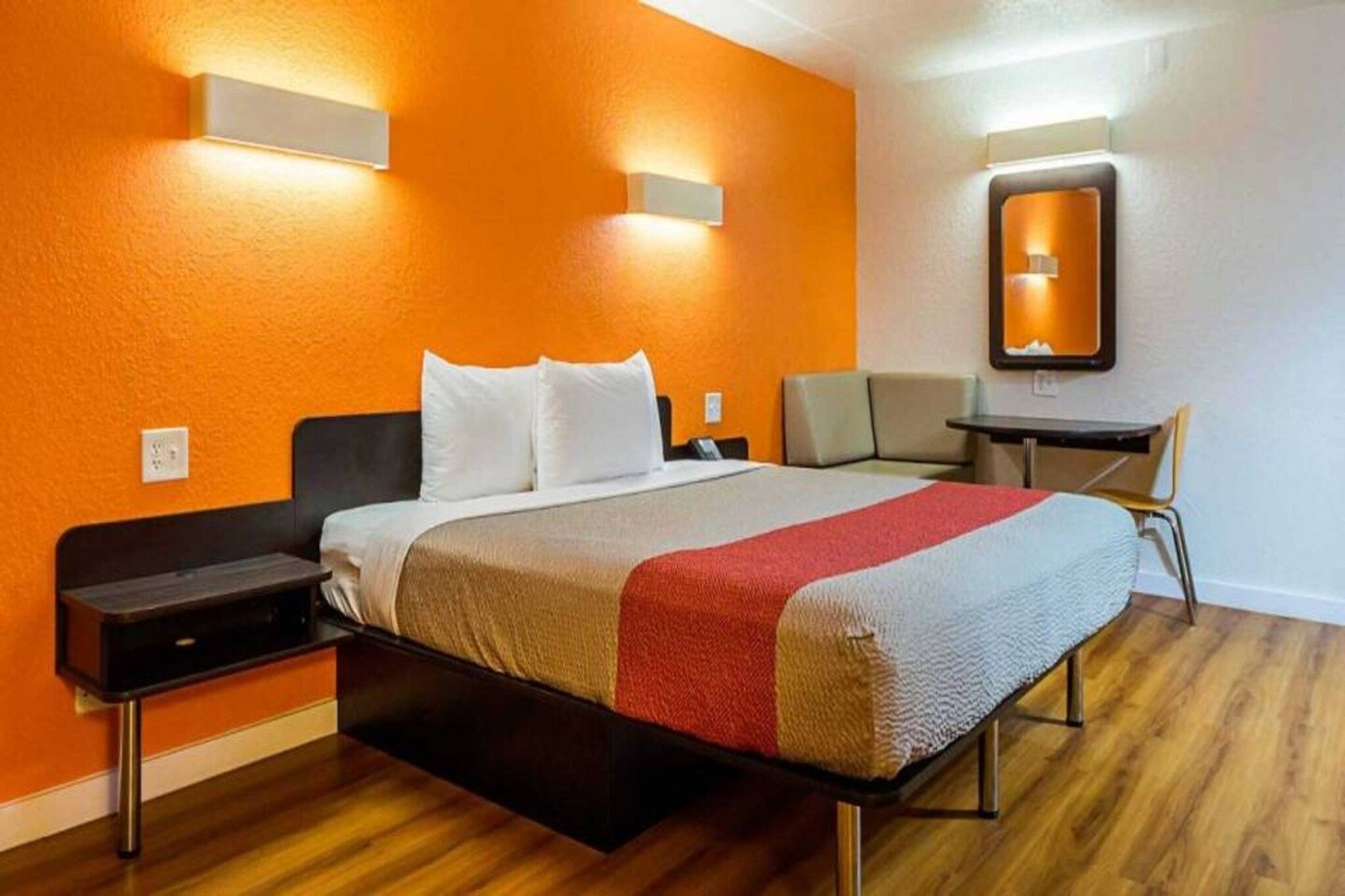 A hotel room with a bed, bedside tables, a desk, and a chair.