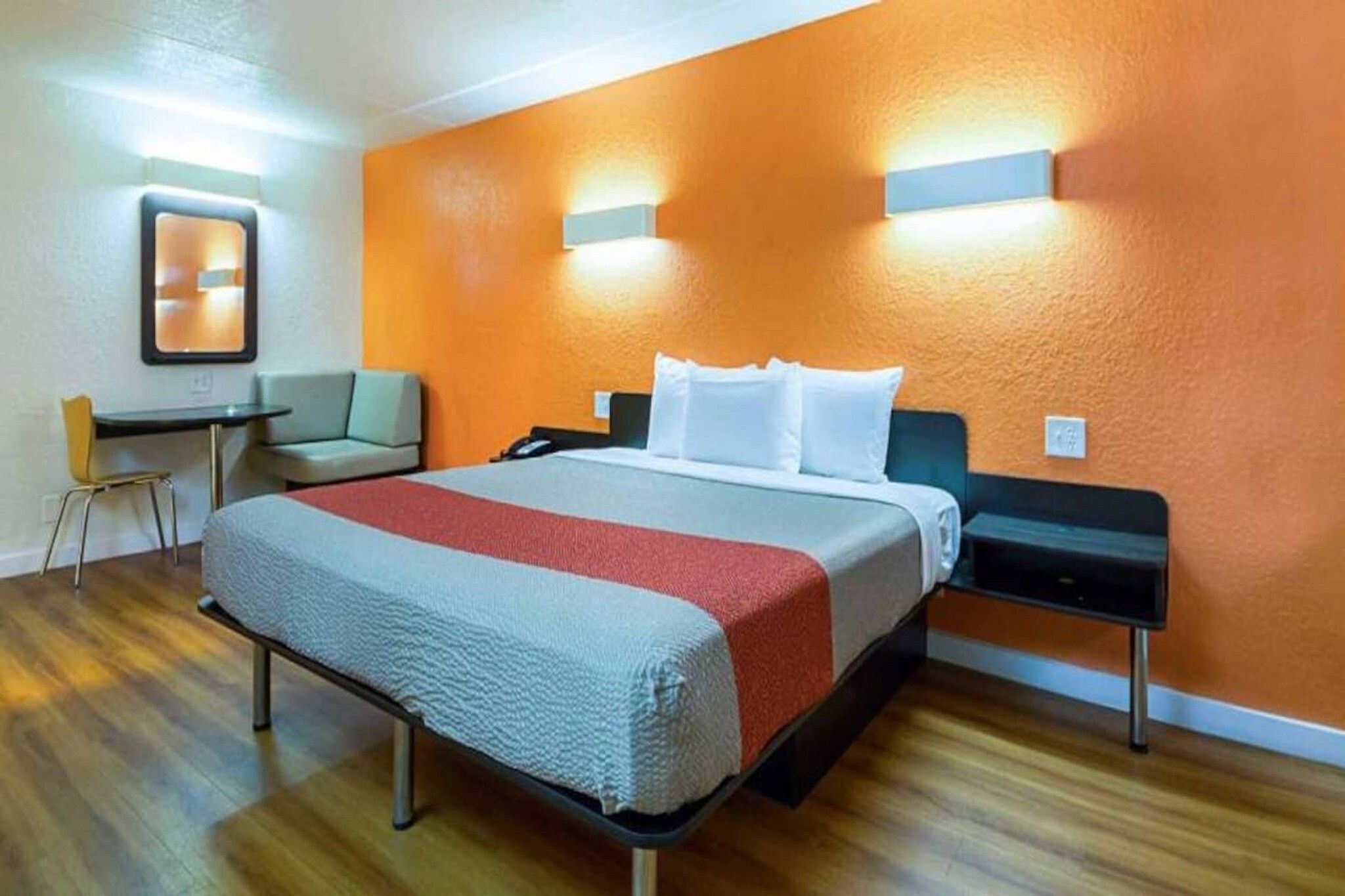 A hotel room with a bed, a desk, a chair, and a nightstand.