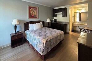A bedroom with a bed, bedside tables, a desk, a chair, and a mirror. - 1 King Bed | Non-Smoking, Kitchen (Fort Worth TX)