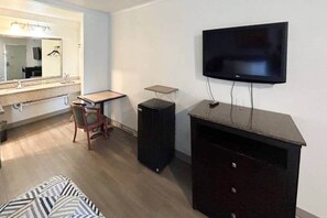 Une chambre d’hôtel équipée d’un lit, d’un bureau, d’une chaise, d’une télévision et d’un haut-parleur.