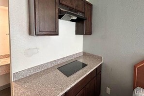 A kitchen with a granite countertop, a built-in stove, and wooden cabinets. - 1 King Bed | Non-Smoking, Kitchen (Fort Worth TX)