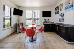 Eine moderne Küche mit Essbereich, inklusive Fernseher, Kühlschrank und Kaffeemaschine.