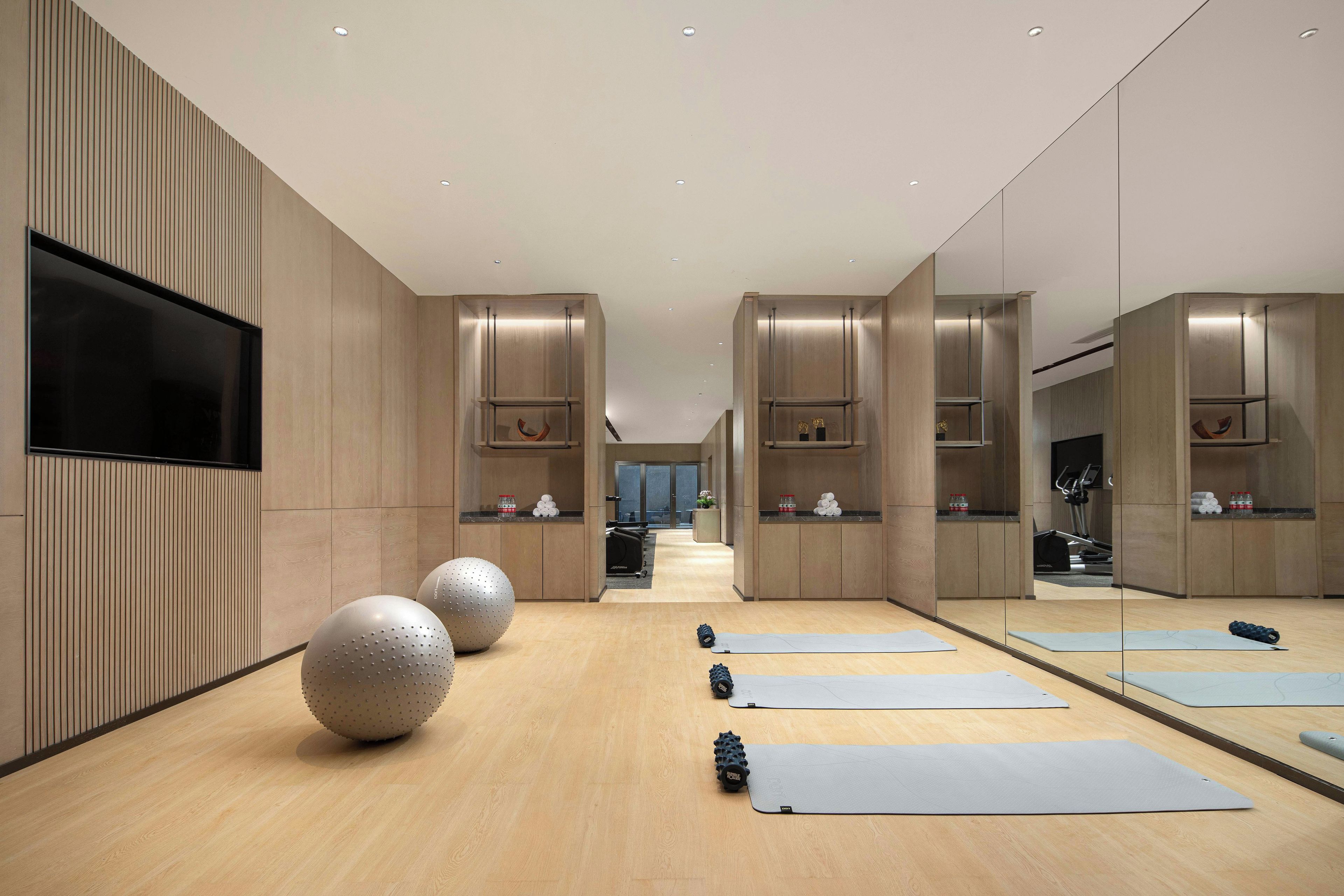 Ein moderner Fitnessraum mit Trainingsmatten, großen Gymnastikbällen und einem Laufband.