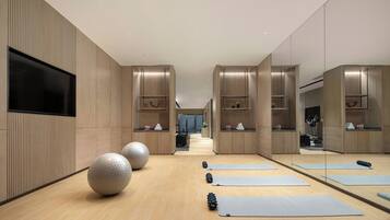 Ein moderner Fitnessraum mit Trainingsmatten, großen Gymnastikbällen und einem Laufband.