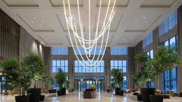 Un'ampia hall con soffitto alto, ampie finestre e un lampadario centrale.