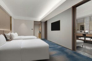 Habitación de hotel con dos camas, un televisor de pantalla plana, un espejo grande y baño con toallas.