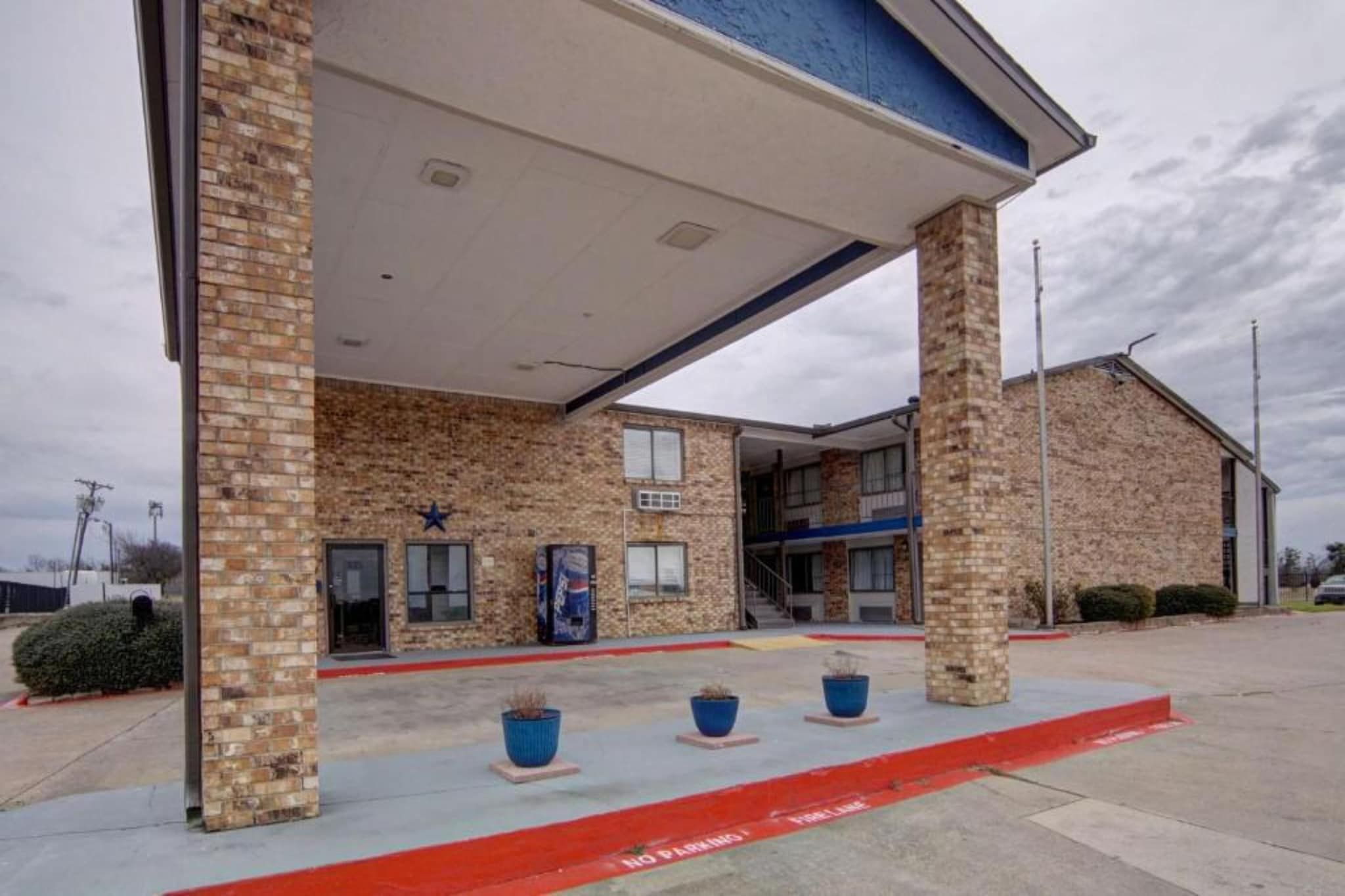 A building with a brick facade, a covered entrance, and a red curb indicating no parking.
