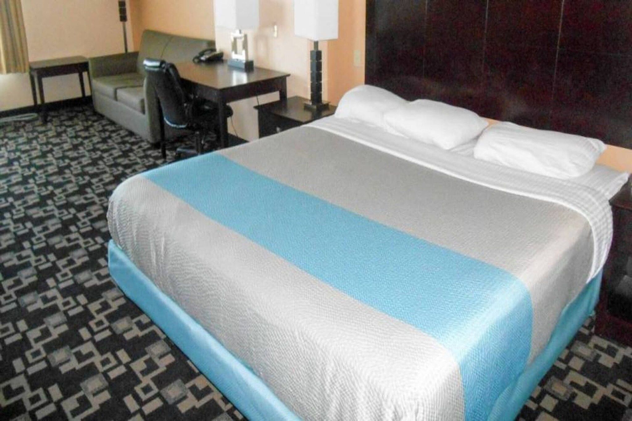 Een hotelkamer met een bed, een bureau, een stoel en een lamp.