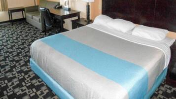 Een hotelkamer met een bed, een bureau, een stoel en een lamp.