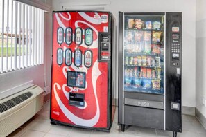 A vending machine with a Coca-Cola logo and a push-button interface, and a refrigerated display case with snacks. - 2 Queen Beds | Non-Smoking (Waco)