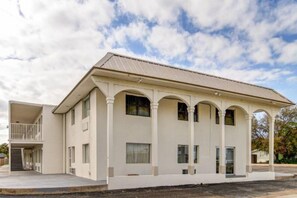 A two-story building with a flat roof, a covered porch with columns, and a staircase leading to a balcony. - 2 Queen Beds | Non-Smoking (Waco)