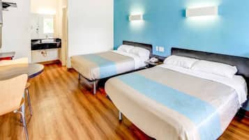 A hotel room with two beds, a desk, a chair, and a bathroom visible in the background.