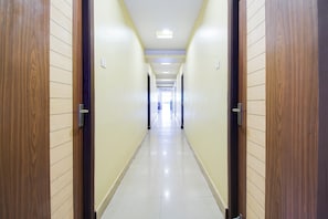 A long, narrow hallway with wooden doors on either side and a tiled floor. - Super OYO Hotel O Allipuram Near Railway (Visakhapatnam)