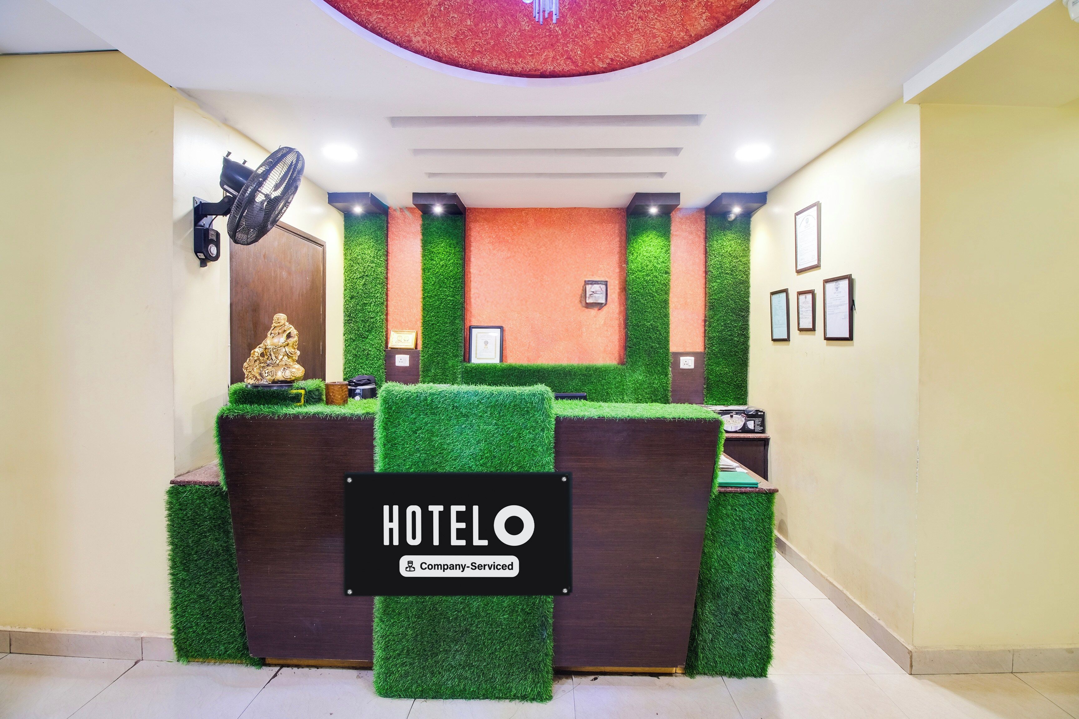 A reception desk with a sign reading 'HOTELO Company Serviced' and a statue on the left.