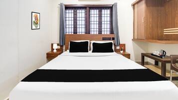A neatly arranged hotel room with a large bed, bedside tables with lamps, a wooden wardrobe, and a window with curtains.