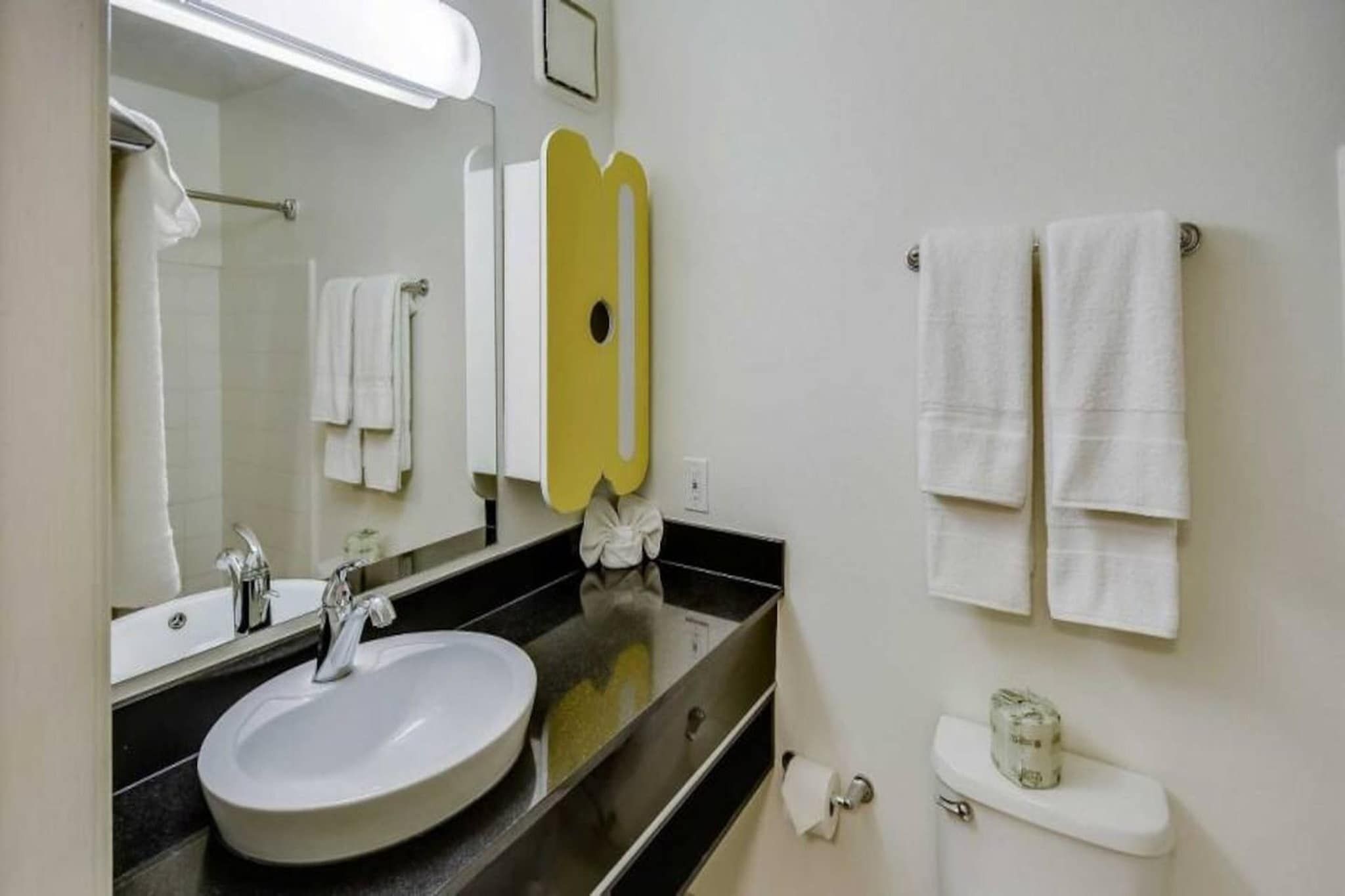 Un baño con lavamanos, espejo, toallero y retrete.