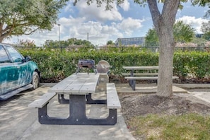 A picnic table with benches, a car, and a tree in a parking lot. - 1 Queen Bed | ADA/Tub, Smoking (Houston)