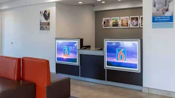 A reception area with two reception desks, a waiting area with red seating, and a wall with framed pictures.
