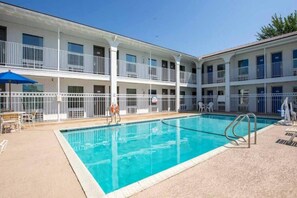 Ett hotell med en swimmingpool, flera balkonger och utomhusmöbler.