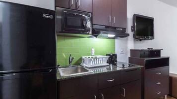 A compact kitchen with a black refrigerator, a microwave, a sink, and a small television.