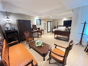 Una habitación de hotel con cama, escritorio, silla, sofá y mesa de comedor.