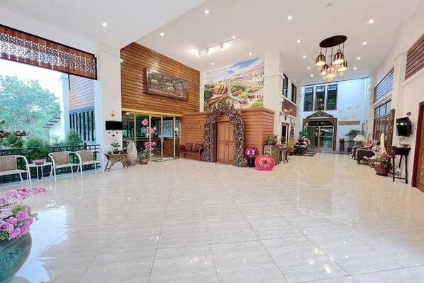 A spacious lobby with a tiled floor, seating areas, and a decorative archway.