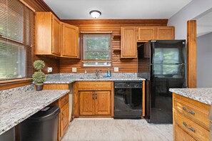Eine Küche mit Holzschränken, Granitabdeckungen, einem Geschirrspüler und einem Kühlschrank.