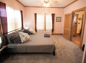 A bedroom with a bed, curtains, a ceiling fan, and a door. - Spacious & Fun Family Home in the Heart of Emporia (Emporia)