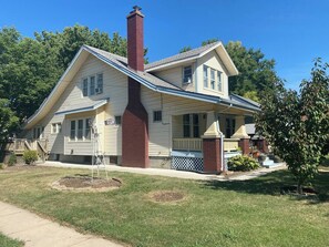 A two-story house with a chimney, a front porch, and a small front yard. - Spacious & Fun Family Home in the Heart of Emporia (Emporia)