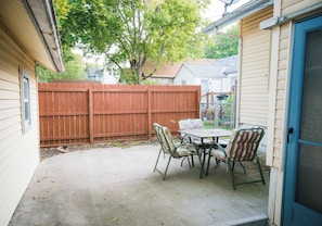 A backyard patio with a table and chairs, a wooden fence, and a screened porch. - Spacious & Fun Family Home in the Heart of Emporia (Emporia)