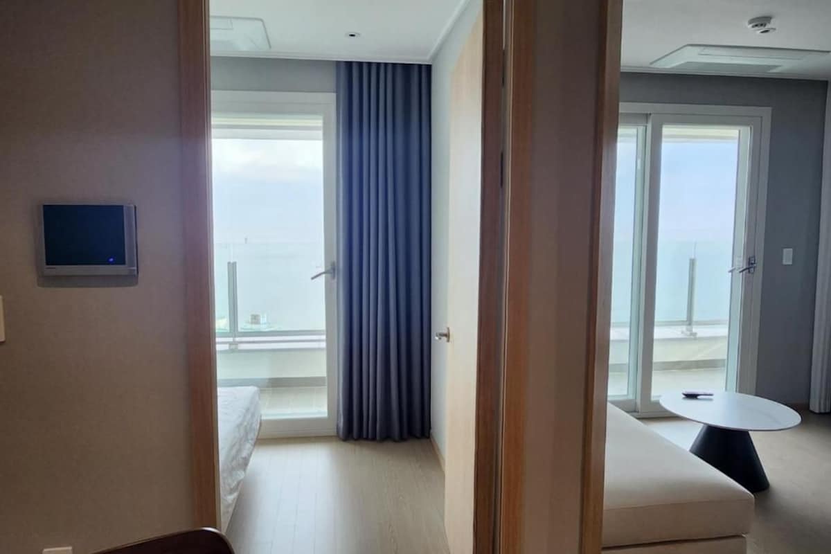 A hotel room with a balcony, a bed, a small table, and a TV.