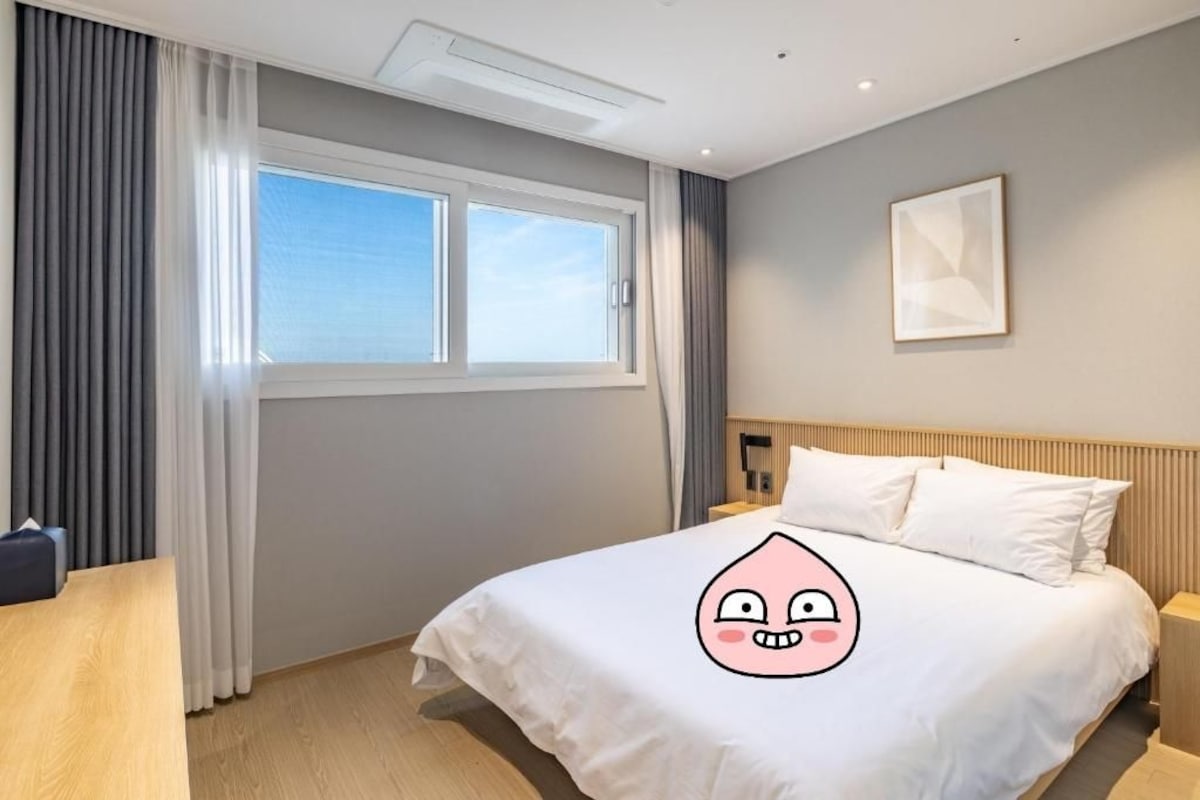 A hotel room with a bed, a desk, and a window with curtains.