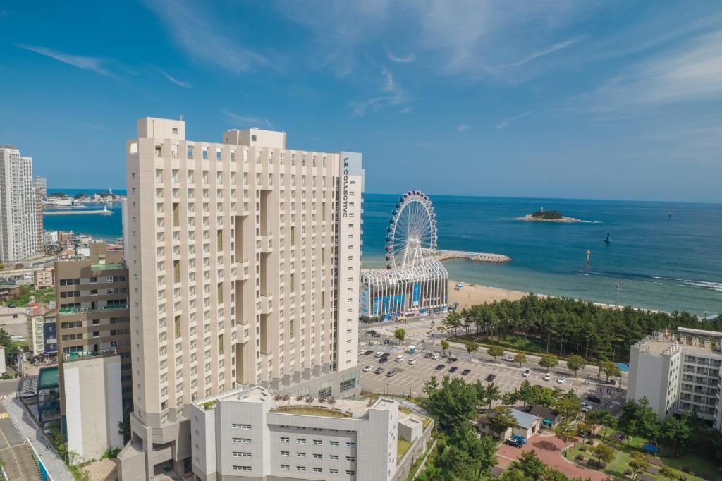 Een hoog hotel met uitzicht op zee en een reuzenrad op de achtergrond.