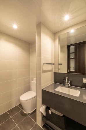 A modern bathroom with a toilet, sink, and mirror. - Richeville Signature Hotel and Residence (Sokcho)