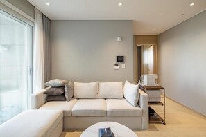 A modern living room with a sofa, a coffee table, and a side table with a lamp. - Richeville Signature Hotel and Residence (Sokcho)