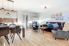 A modern living room with a sofa, chairs, a coffee table, and a dining area with chairs and a table. - Holiday apartment with 2 bedrooms (St. Peter-Ording)